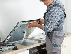 Appliance repair technician installing a built-in cooktop in Rochester, NY