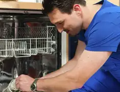 Dishwasher repair technician inspecting and servicing an open dishwasher in Rochester, NY