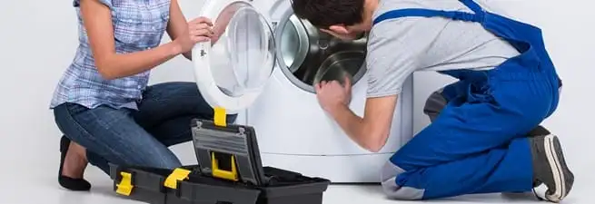 Washer repair technician inspecting a front-load washing machine with tools in Rochester, NY