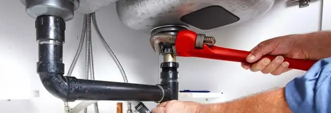 Garbage disposal repair technician tightening the sink drain and disposal connection in Rochester, NY