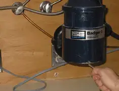 Garbage disposal repair technician tightening the mounting ring under a sink in Rochester, NY