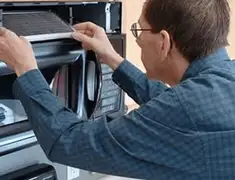 Appliance repair technician replacing a microwave vent filter in Rochester, NY