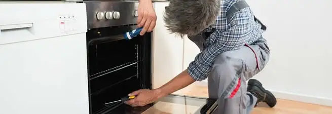 Oven repair technician inspecting and servicing an electric oven in Rochester, NY