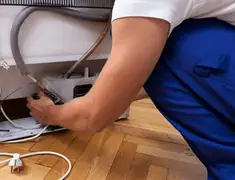 Appliance repair technician fixing refrigerator water line and connections in Rochester, NY