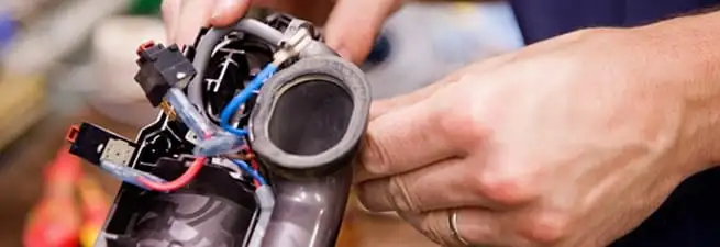Vacuum repair technician reconnecting wiring and components in Rochester, NY