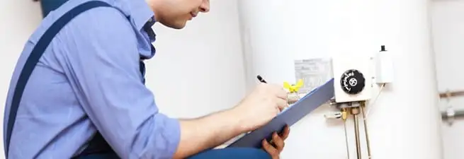 Water heater repair technician inspecting the unit and recording service notes in Rochester, NY