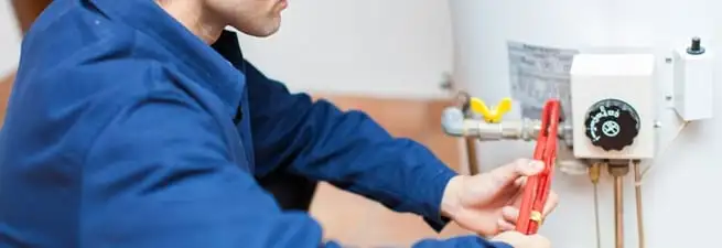 Water heater repair technician adjusting the temperature control and gas valve in Rochester, NY